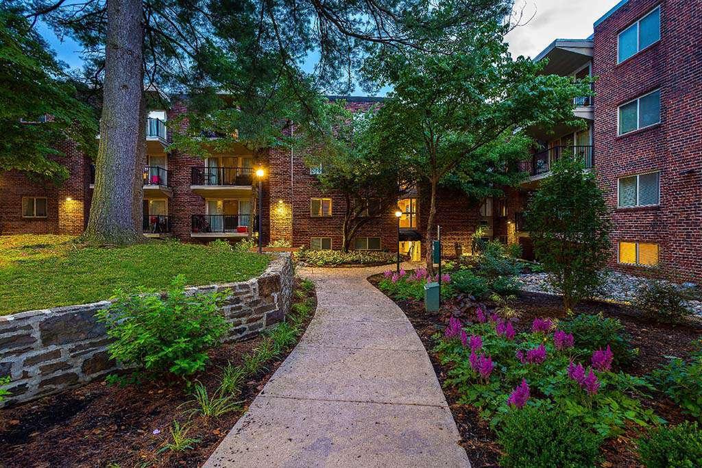 Entrance walkway to residential building lined with purple flowers at Haverford法院 apartments